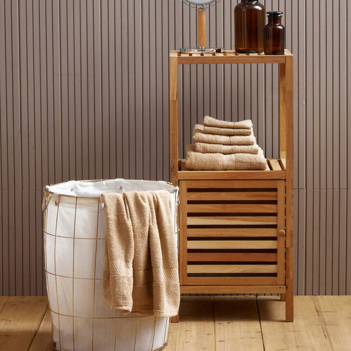 Bathroom setting with wooden shelf, round mirror, and towels against a striped wall.