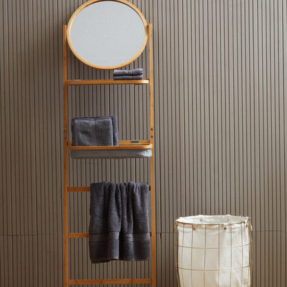 Towel rack with round mirror and shelves against a striped wall with a laundry basket on wooden floor.