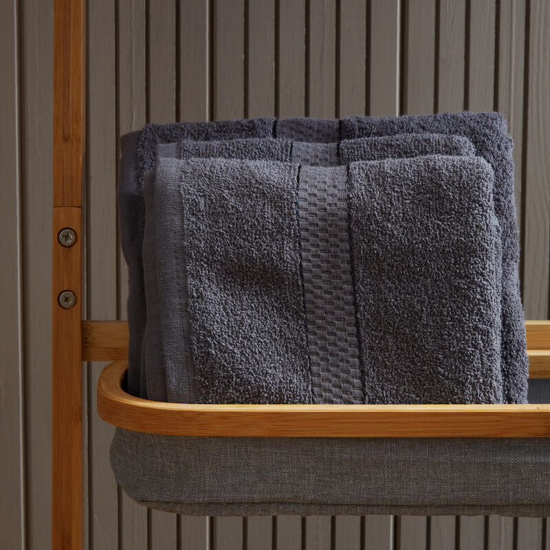 Stack of gray towels on a wooden shelf against a neutral wall.