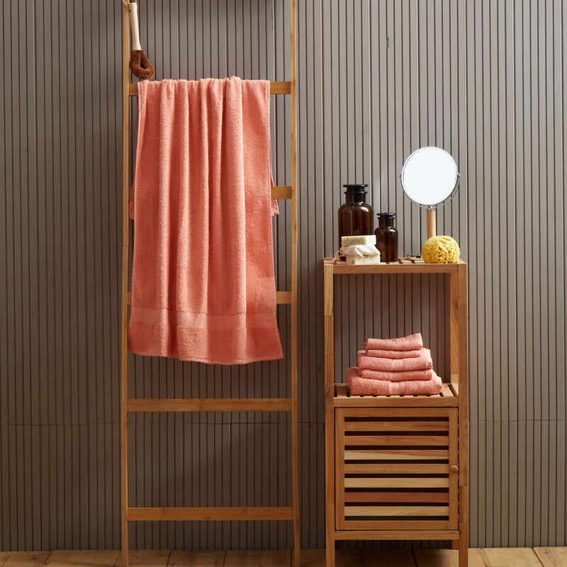 Bamboo towel rack with pink towel against a striped wall.