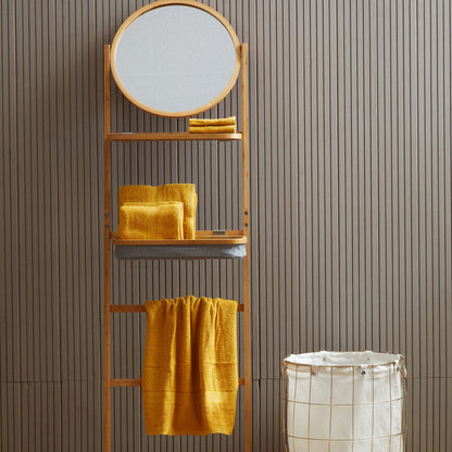 Towel rack with round mirror and yellow towels against a striped wall.