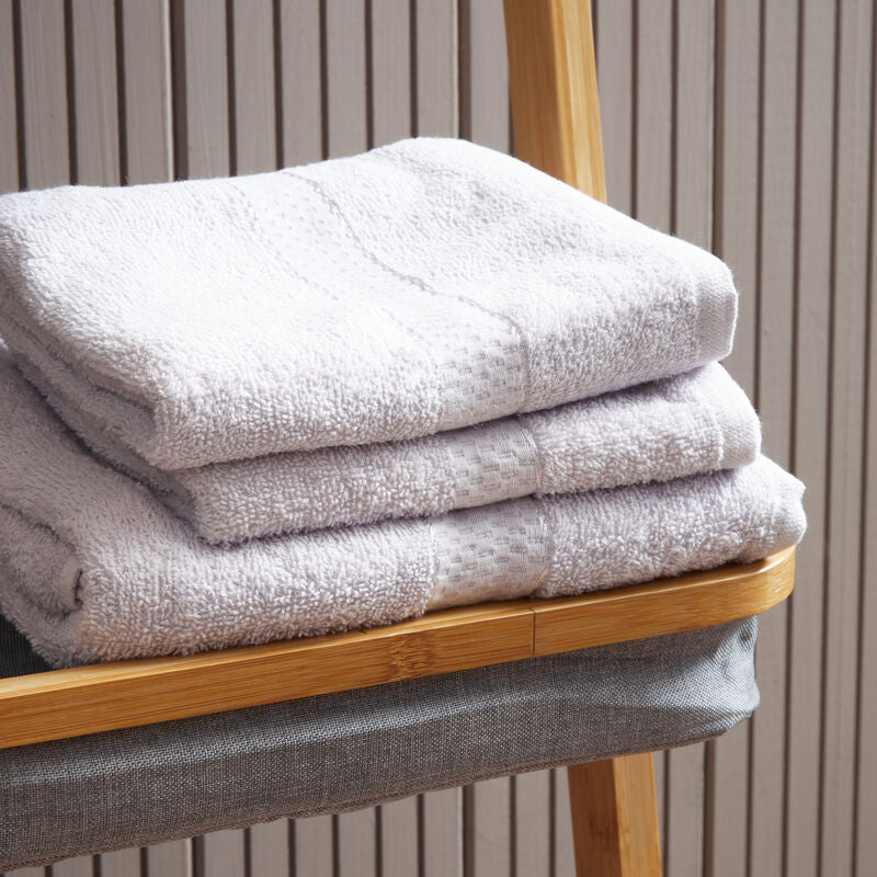 Stack of white towels on a wooden towel rack against a striped wall.