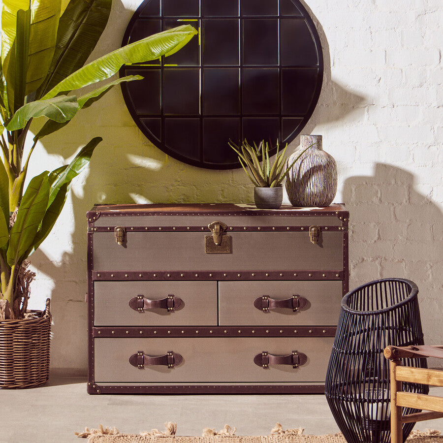 Vintage-style chest of drawers with decorative items against a white brick wall.