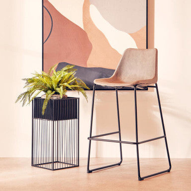 Modern bar stool with a plant and abstract wall art in a minimalistic setting