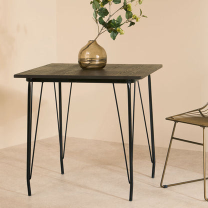 Small table with a vase and plant next to a chair on a beige background