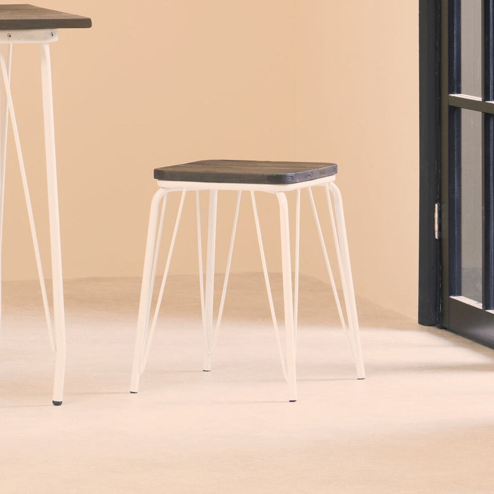 Stool with a black seat and white metal legs in a minimalistic room.