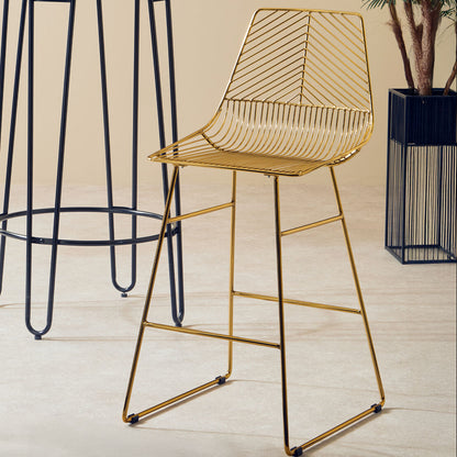 Gold wire bar stool next to a black metal bar stool on a light wooden floor.