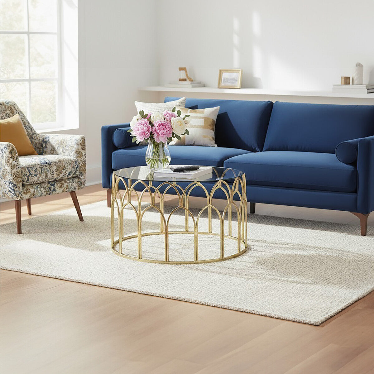Modern living room with a blue sofa, gold coffee table, and floral arrangement.