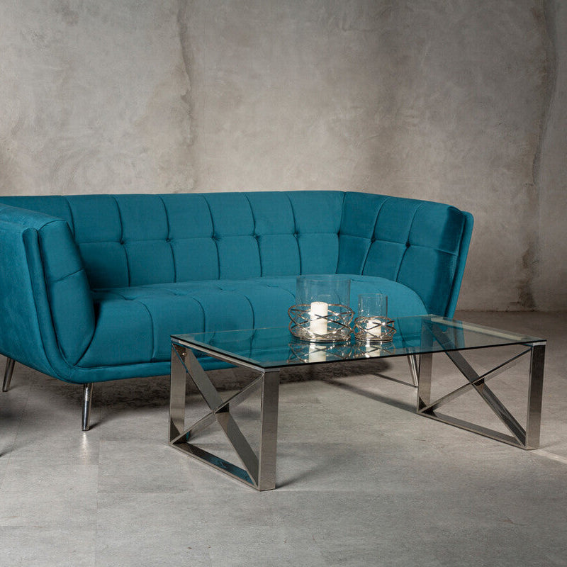 Modern living room with a blue sofa, glass coffee table, and decorative lamp against a gray wall.