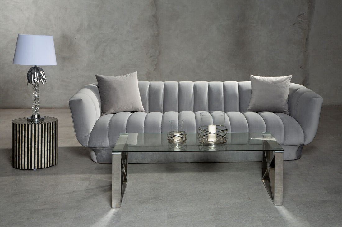 Gray sofa in a modern living room with a glass coffee table and decorative items.