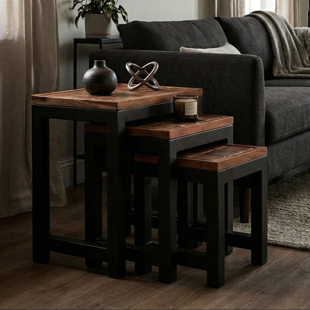 Nest of wooden tables in a living room setting with a gray sofa and decorative items.