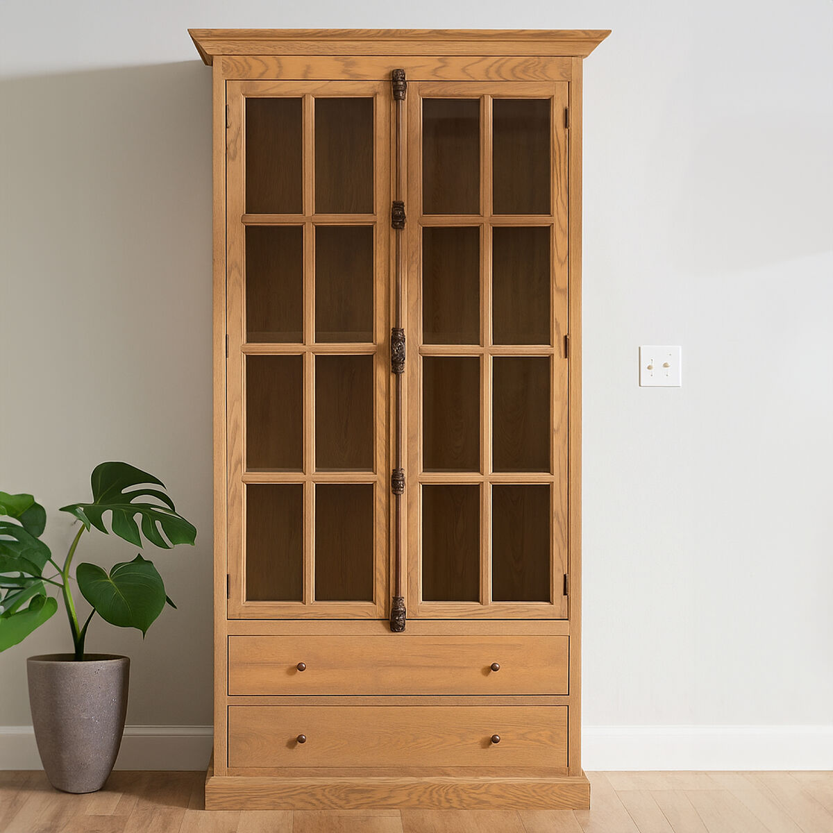 Wooden cabinet with glass doors and drawers in a room with a plant and wall socket.