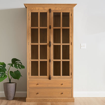 Wooden cabinet with glass doors and drawers in a room with a plant and wall socket.