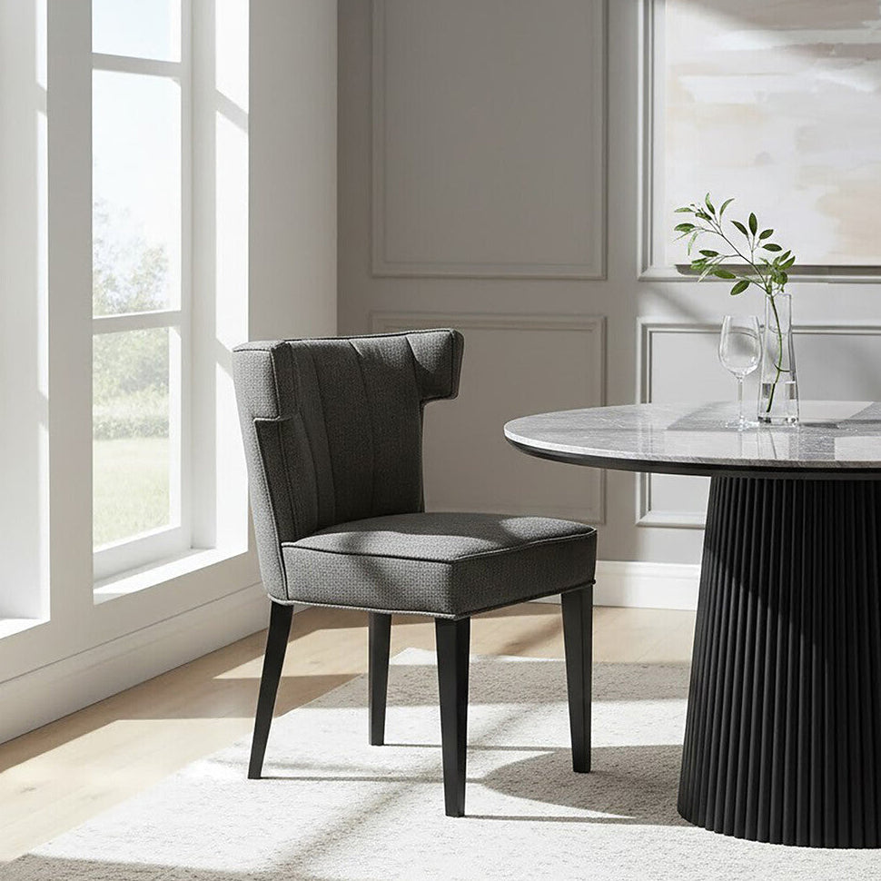 Dining room with a black chair and round table near large windows.