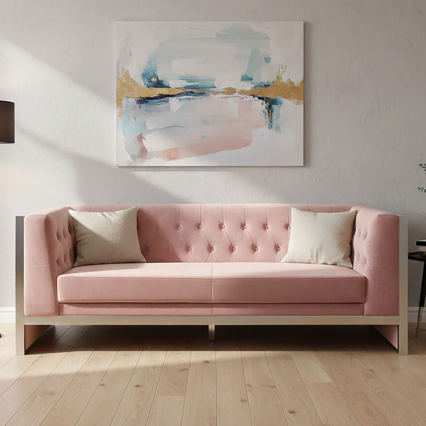 Pink sofa in a living room with abstract art on the wall and a lamp.