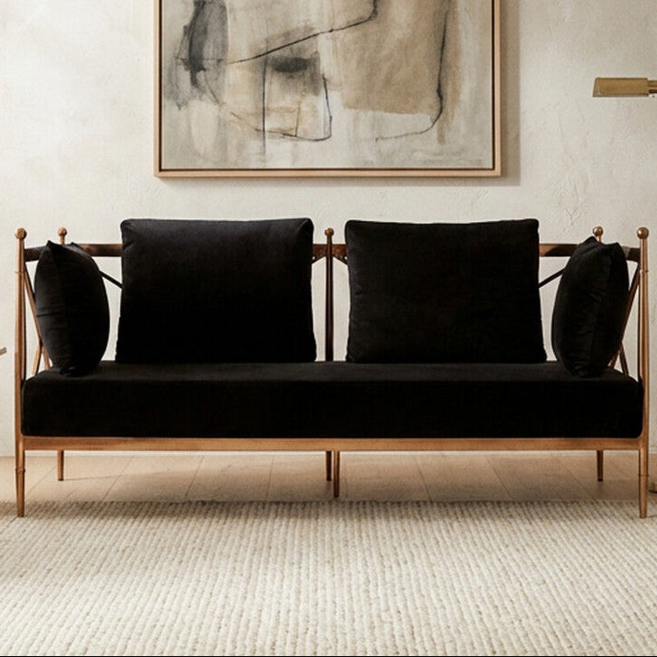 Modern living room with a black sofa, abstract art, and a plant.