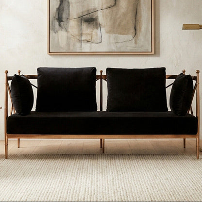 Modern living room with a black sofa, abstract art, and a plant.