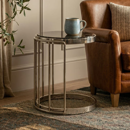 Small round table with a mug on it next to a brown leather armchair in a cozy room.