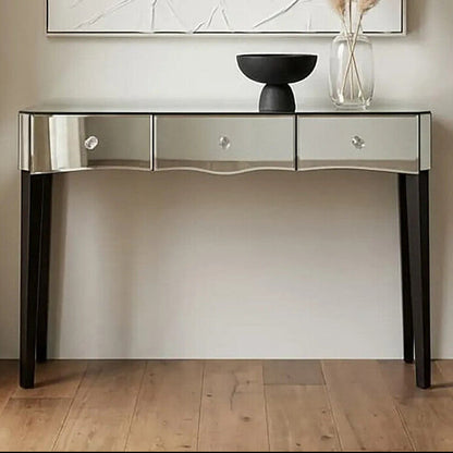 Decorative console table with a mirror finish against a neutral wall with abstract art and pampas grass.