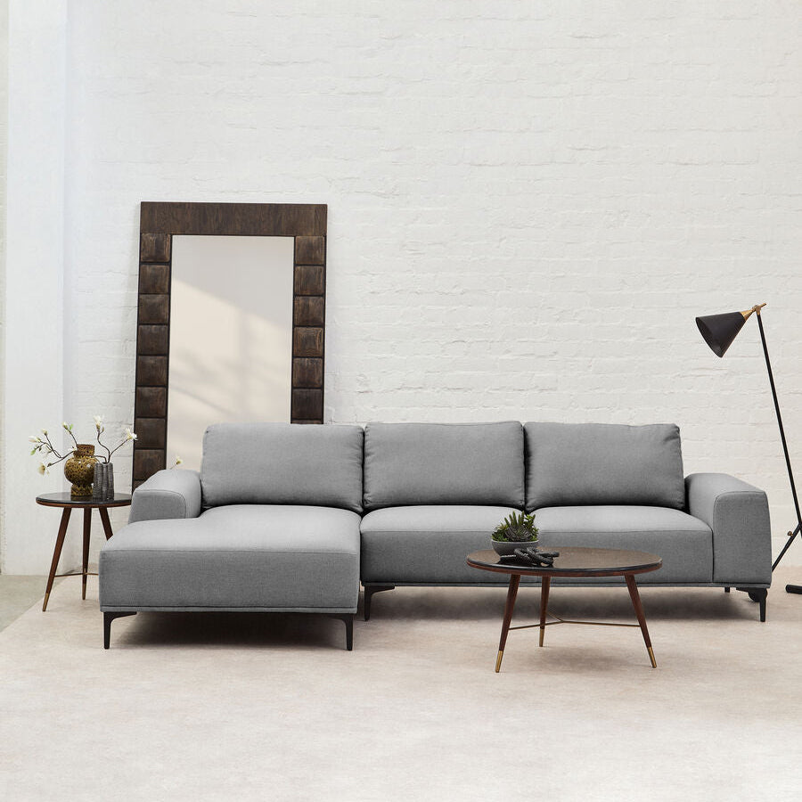 Gray sectional sofa in a modern living room with a mirror and lamp.