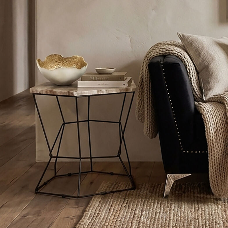 Cozy living room with a black sofa, beige blanket, and side table.