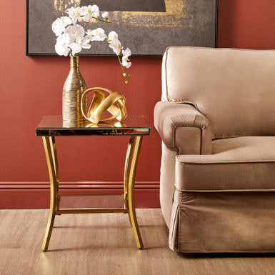 Beige sofa in a living room with a gold side table, white flowers, and abstract art on the wall.