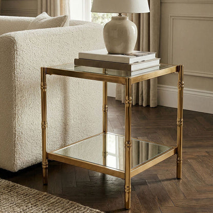 Living room with a gold side table, white sofa, and lamp.
