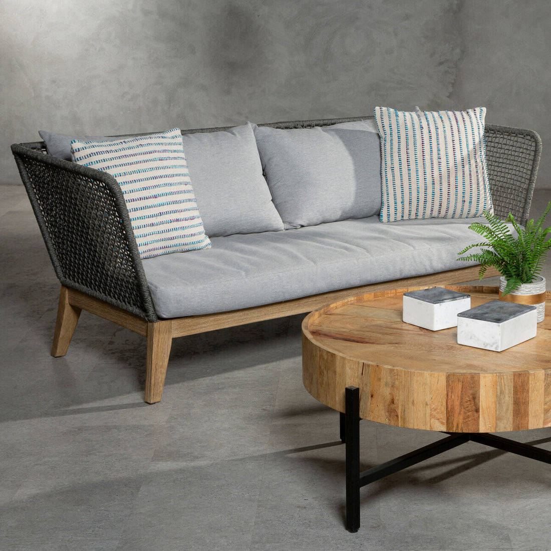 Outdoor furniture set with a sofa and coffee table on a concrete floor.