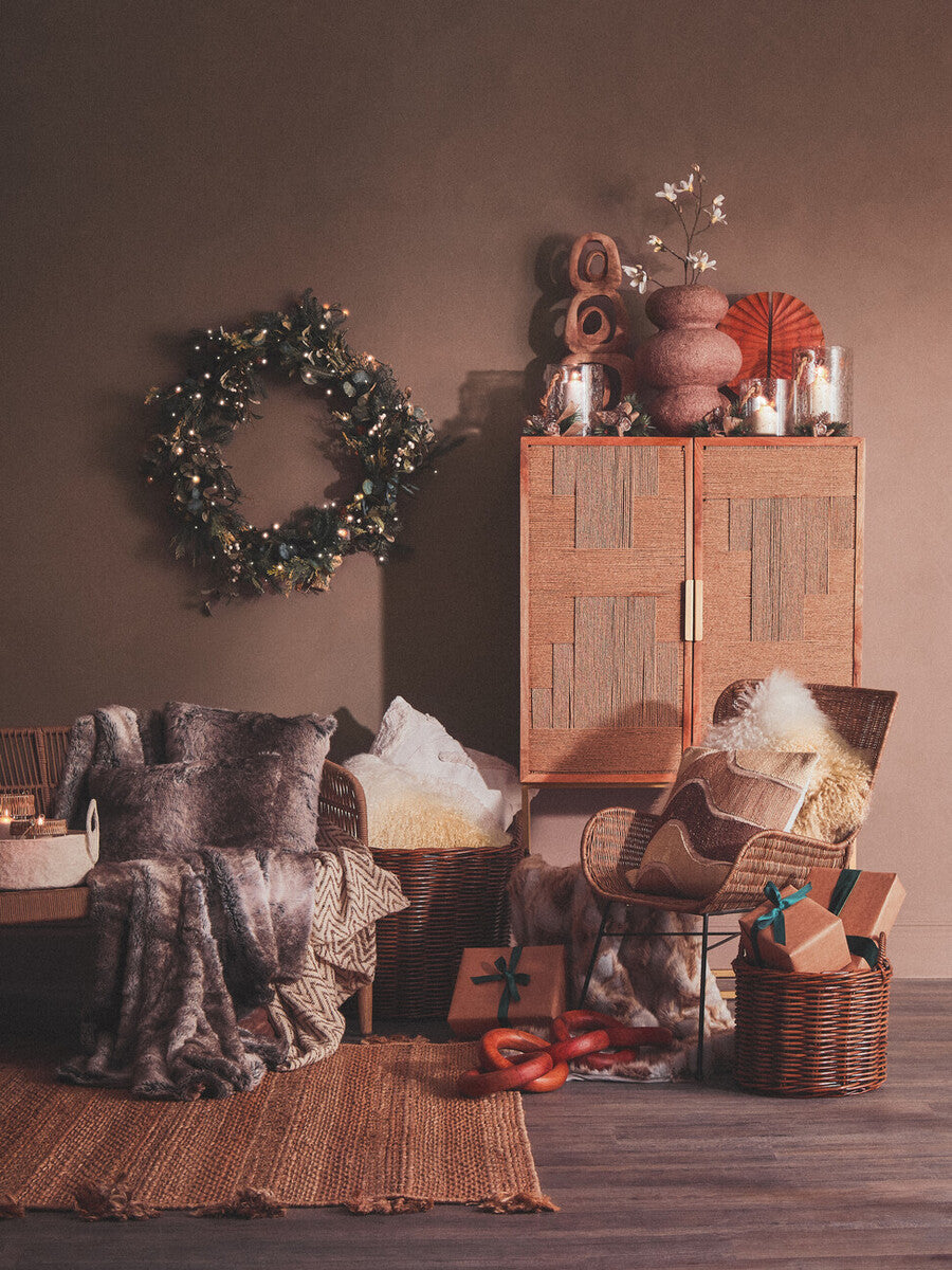 Cozy living room with wooden cabinet, wreath, and decorative items.