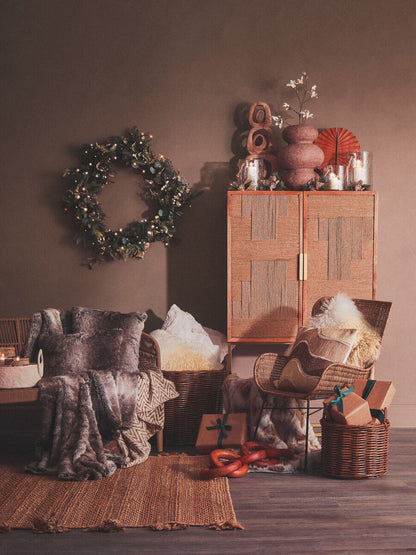 Cozy living room with wooden cabinet, wreath, and decorative items.