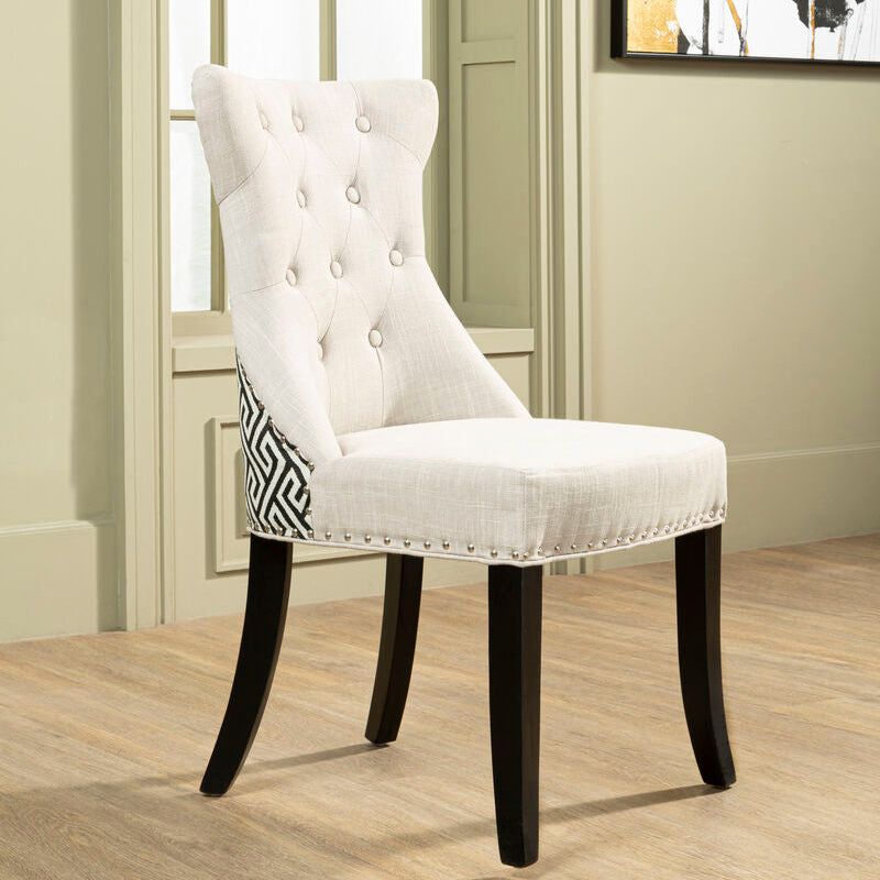 White upholstered chair with black legs in a room with wooden flooring and a window.