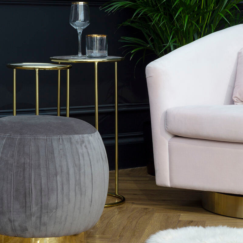 Modern living room with a gray ottoman, gold side table, and white sofa.