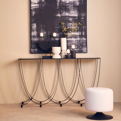 Modern console table with decorative items against a beige wall with abstract art.