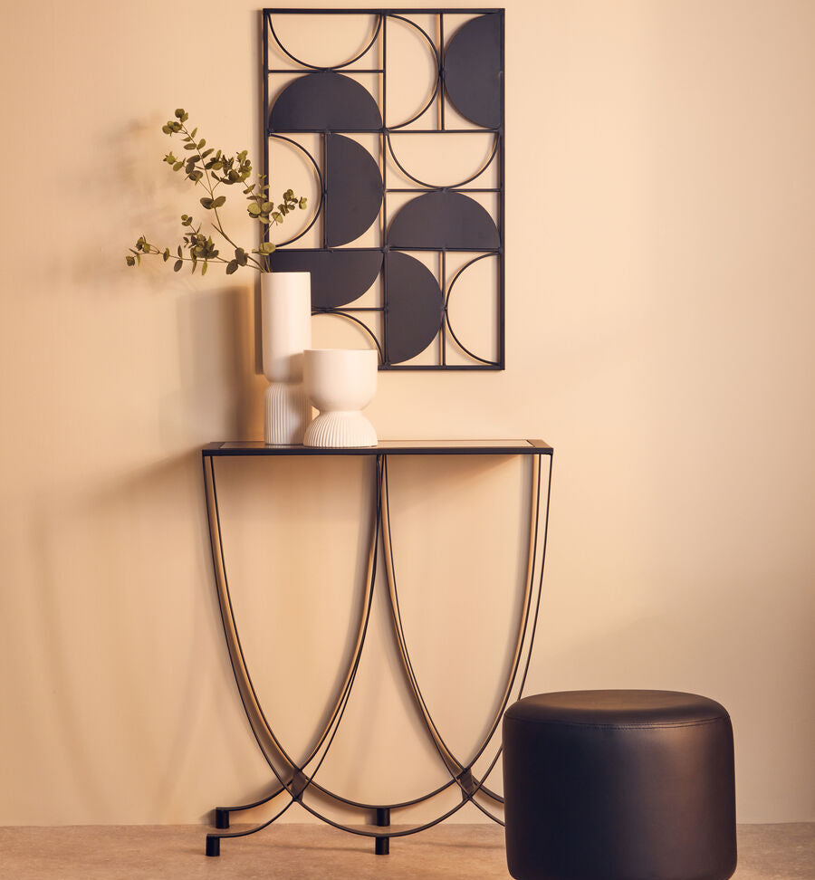 Modern console table with decorative items against a beige wall