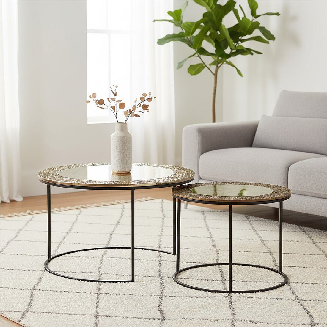 Two round coffee tables with a vase and plant in a living room setting.
