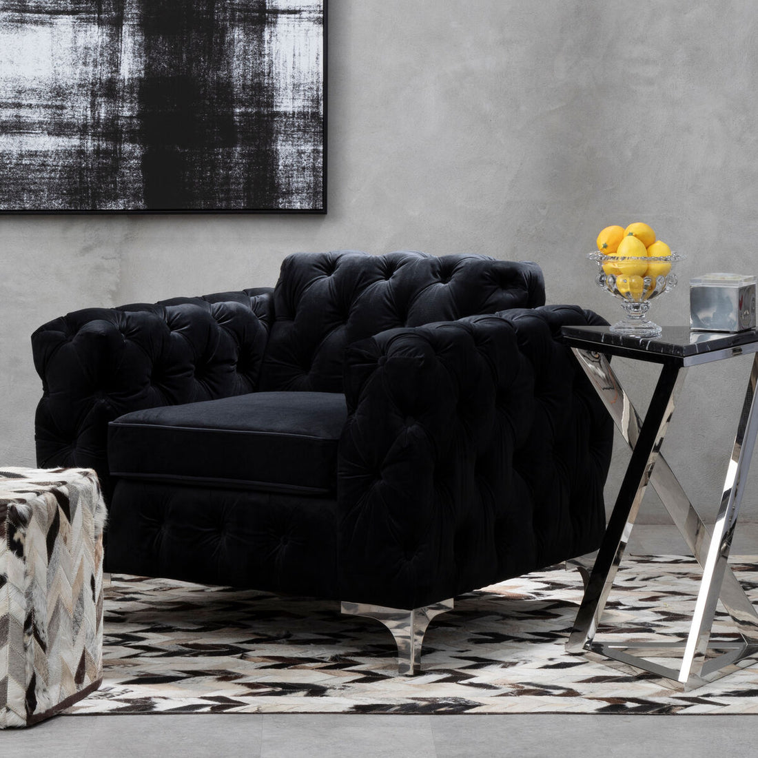 Black tufted sofa in a modern living room with abstract art and a side table.