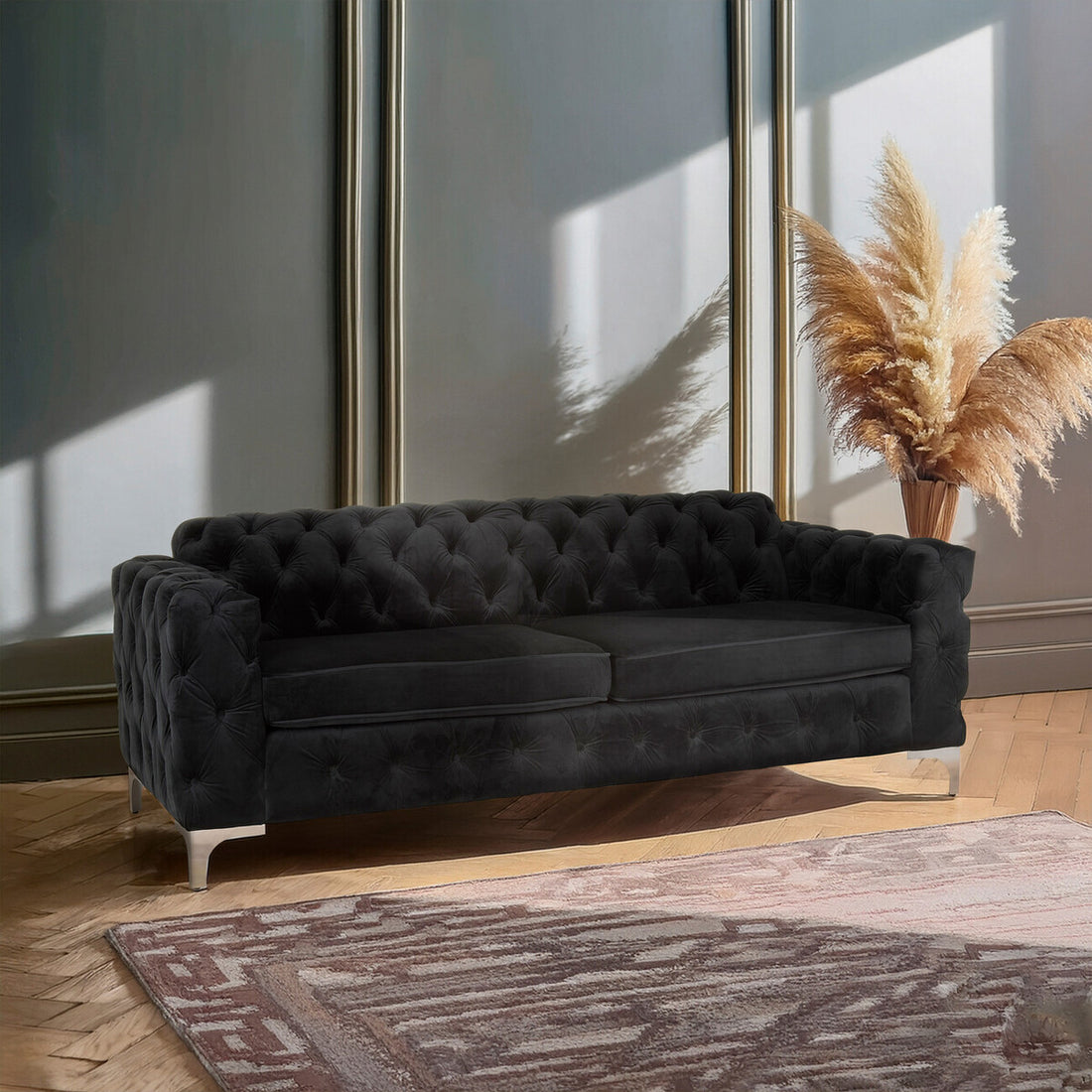 Black tufted sofa in a room with a large mirror and decorative plant.