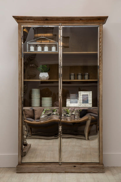 Wooden display cabinet with mirrored doors against a white wall
