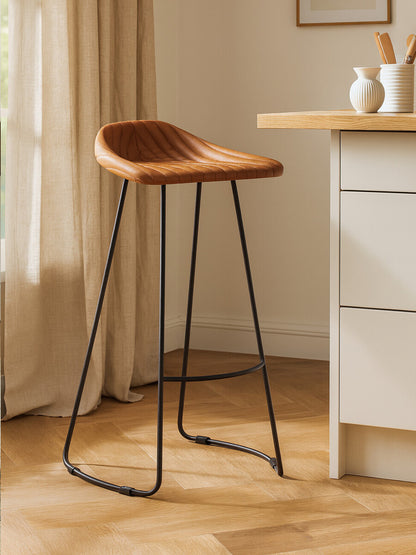 Wooden bar stool with black metal legs in a home setting.