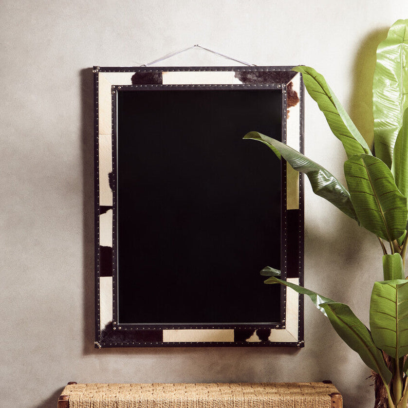 Decorative mirror with wicker bench and plant on a patterned rug