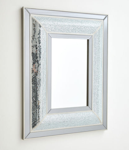 Silver framed mirror with textured border on a white wall