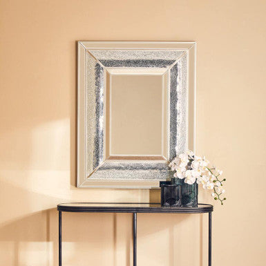 Decorative mirror with a black console table against a beige wall