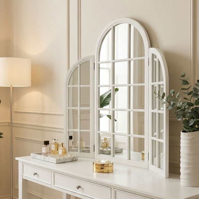 White arched mirrors on a dresser with decorative items in a room.