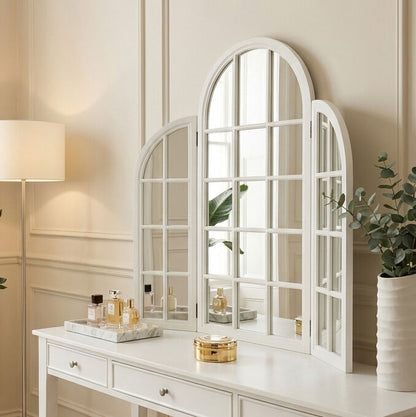 White arched mirrors on a dresser with decorative items in a room.