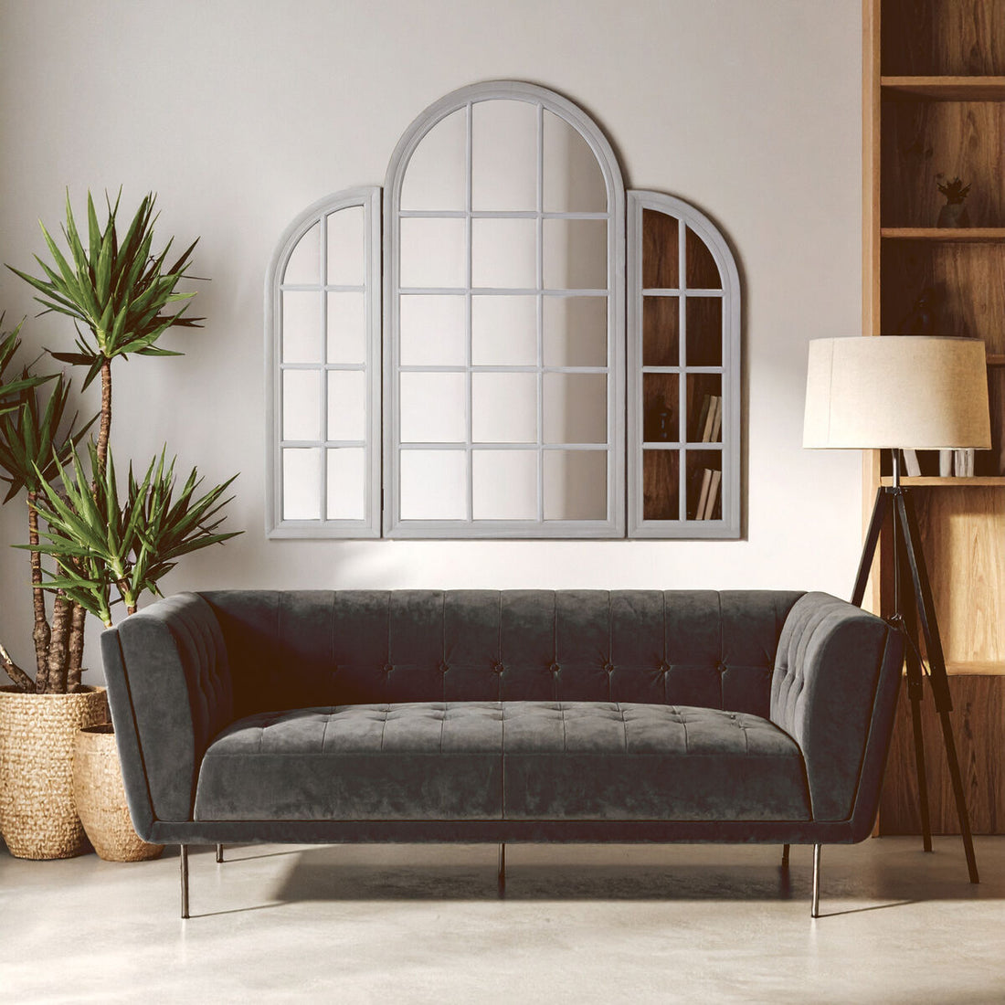 Gray sofa in a room with a large mirror, plants, and a lamp.