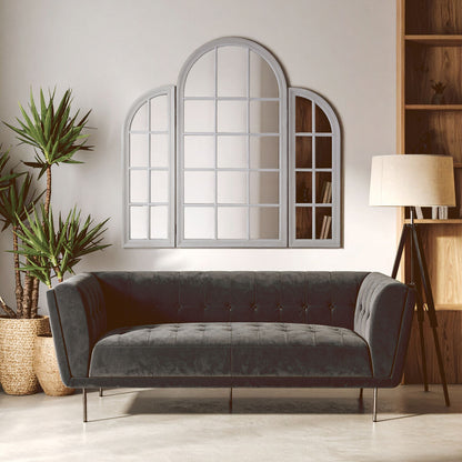 Gray sofa in a room with a large mirror, plants, and a lamp.