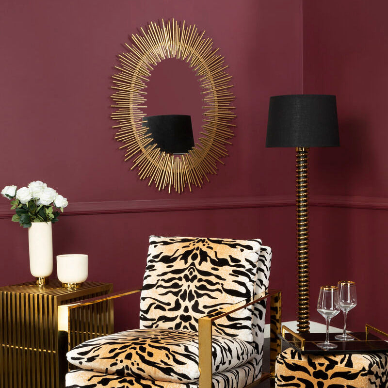 Decorative room with a gold-framed mirror, tiger print chair, and ottoman against a purple wall.