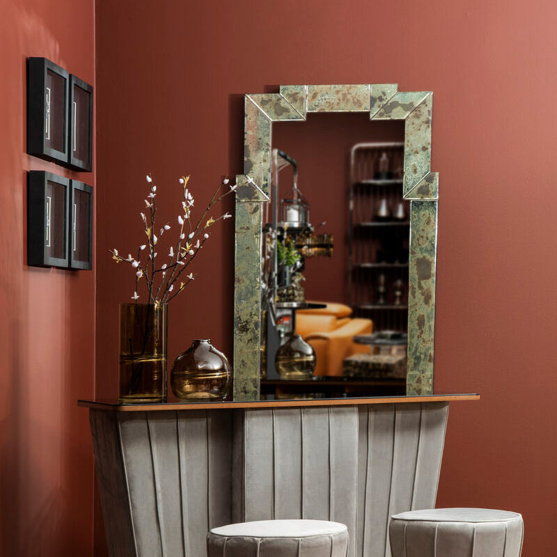 Modern bar setup with marble mirror, stools, and decor against a red wall.