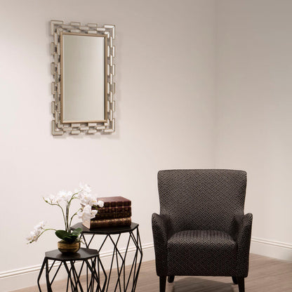 Modern living room with a gray armchair, geometric side table, and decorative mirror.