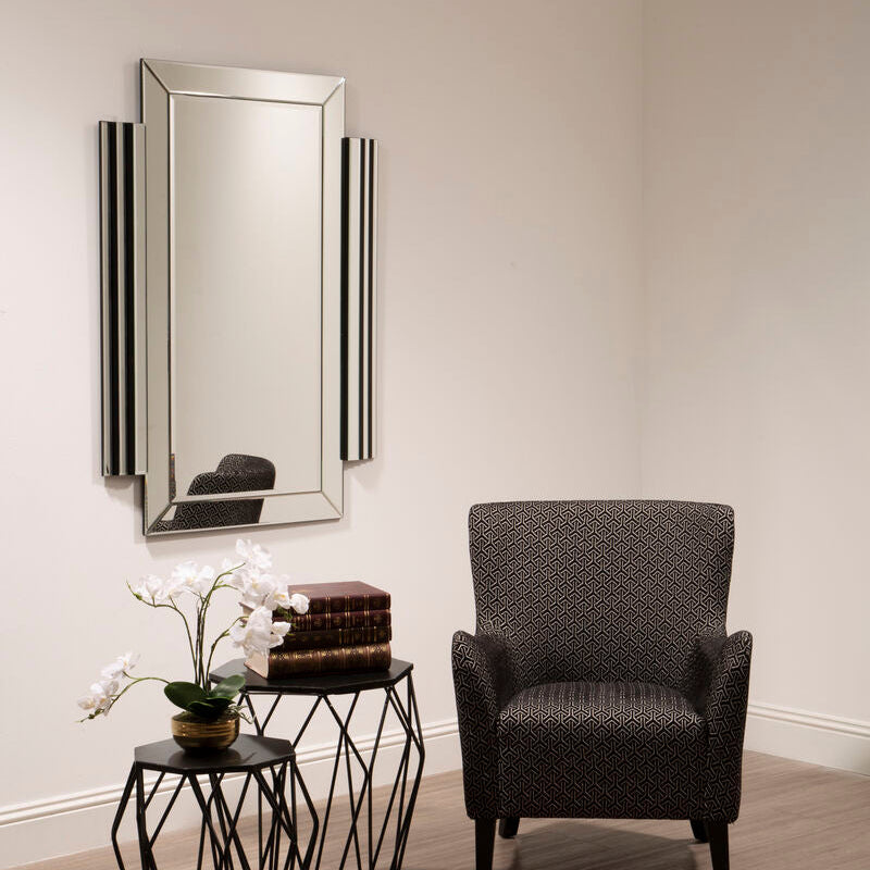 Modern interior with a dark armchair, geometric side table, and decorative mirror.
